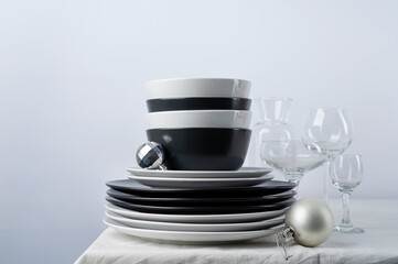 Set of black and white tableware with plates, cutlery and glasses with holiday decorations on dining table, copy space