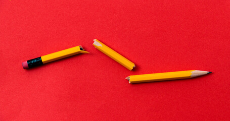 Broken pencil on red background