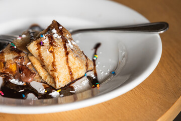 Stuffed sweet crepes with chocolate syrup, close up