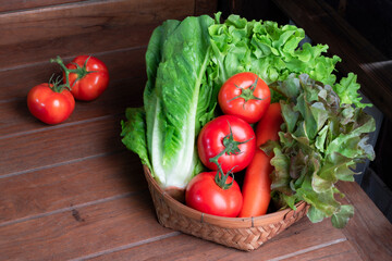 Healthy food vegetable red lettuce and romaine tomato carrot in basket on wood table, top view, copy space.