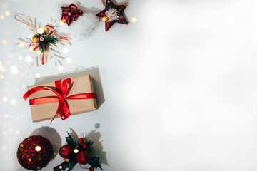 A gift wrapped in brown paper and tied red ribbon with toy star, a red ball and snowflake on a...