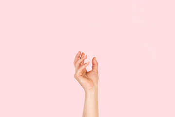 Mano de mujer en posición para sostener algo sobre un fondo rosa liso y aislado. Vista de frente y de cerca Copy space - obrazy, fototapety, plakaty