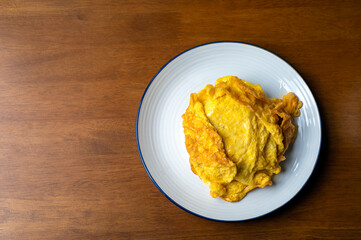 Top view of omelet in a plate on wooden table with copy space, Thai omelet style, Fried egg, Fast food, Copy space.