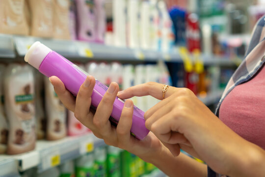 Close-up of a young woman's hands reading information on a bottle of shower gel in a store. Buying cosmetics in the store. Shopping trip.
