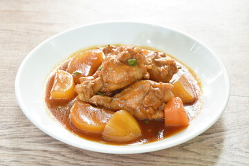 boiled chicken leg with potato in swet red gravy sauce stew on plate