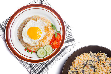 Fried rice served with fried egg, sliced ​​tomato, green chili and cucumber in plate isolated on white background. top view.