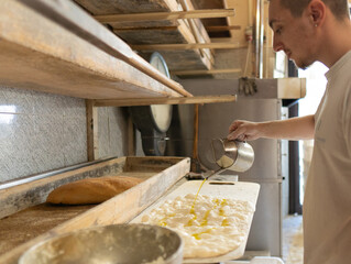 Young baker prepares bread to take on oven and bake it in traditional way