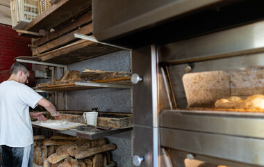 Young baker prepares bread to take on oven and bake it in traditional way