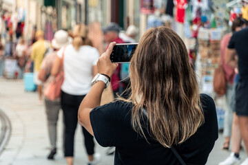Tourist woman taking a photo with the smartphone of a famous place in the city of Porto, Portugal,...