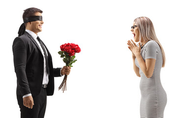 Man with blindfold giving a bunch of red roses to an excited young woman