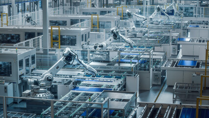 Large Production Line with White Industrial Robot Arms at Modern Bright Factory. Solar Panels are...