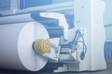 Modern machine for cutting large rolls of white paper for printing houses with roll high-speed...