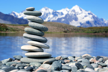 pyramid of smooth stones on the background of a mountain lake. natural balance of life.