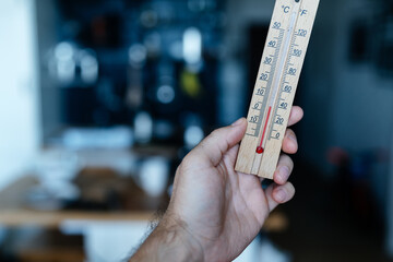 Energy crisis in Europe. A man's hand holds a thermometer with a temperature close to zero in his apartment.