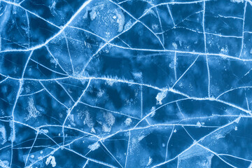 Ice on a frozen river. Background texture of blue ice with cracks in the snow. drone view.