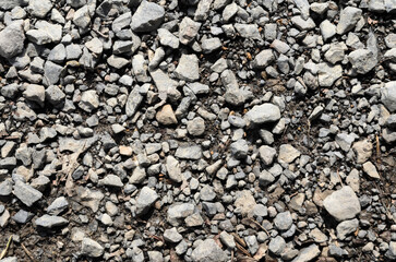 Abstract background with crushed gravel and small little grey rocks and stones, close-up view from directly above
