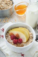 Oatmeal. Bowl of oatmeal porridge with raspberry, pear and honey on gray concrete old table background. Hot and healthy food for Breakfast, top view, flat lay