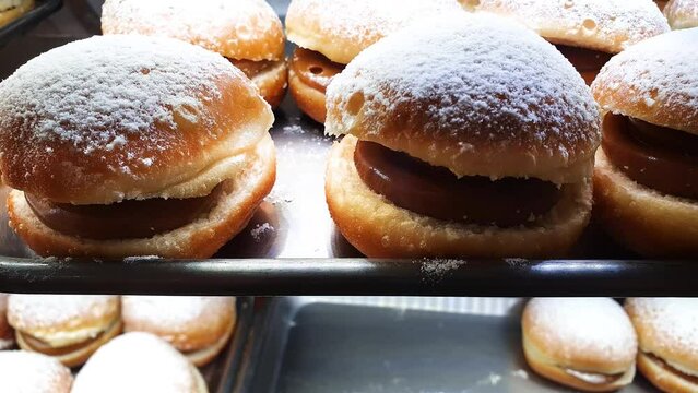 Brazilian donut with dulce de leche filling being displayed through the showcase of a Brazilian bakery.