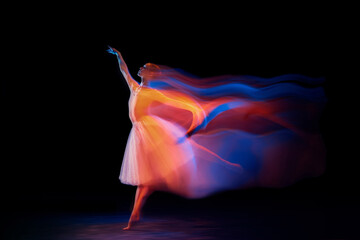 Dance of light and glow. Beautiful grace girl, female ballet dancer dancing isolated over black background in mixed neon light.