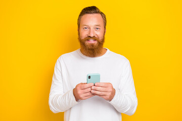 Photo of young successful influencer guy wear white shirt hold phone typing girlfriend app ad isolated on bright yellow color background