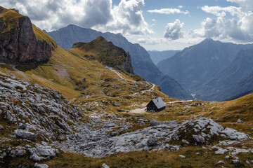 Mangart in Slowenien, Blick auf eine Berghütte und den dahinterliegenden Alpen bei bewölktem Himmel