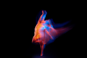 Like a phoenix. Solo performance of flexible adorable male ballet dancer isolated on dark...