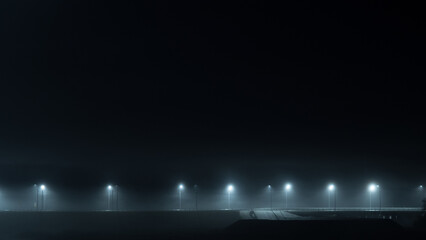 Night foggy highway illuminated by lampposts. Autumn foggy landscape