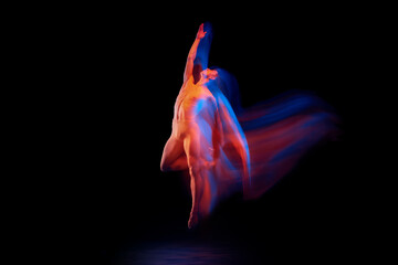 Young graceful and flexible shirtless male ballet dancer dancing isolated on dark background in...