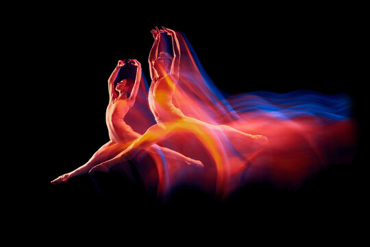Freedom. Couple of graceful and fragile ballet dancers in action isolated over black background in mixed neon light. Futurism, fantasy, miracle.