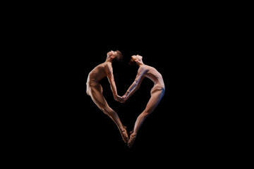 Love. Couple of graceful and flexible ballet dancers making heart shape of their bodies isolated over black background. Art, care, support