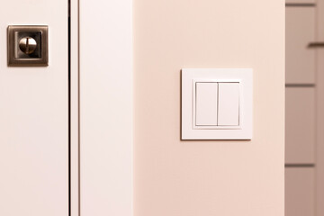 White electrical switch on beige wall next to the door in modern apartment