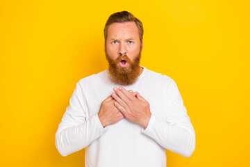 Portrait photo of young funny grimace red hair man unhappy upset touch chest ill impressed isolated on yellow color background