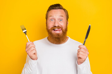 Photo of attractive young man hold fork knife eat breakfast lick lips hungry wear stylish white...