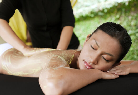 Woman receiving avocado body scrub at a resort spa. Bali, Indonesia.
