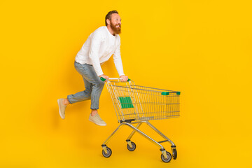 Full body profile photo of beard man run trolley wear shirt jeans shoes isolated on yellow color background