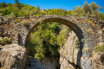 Ancient bridge over the Koprucay river gorge in Koprulu national Park in Turkey. Panoramic scenic view of the canyon and blue stormy mountain river
