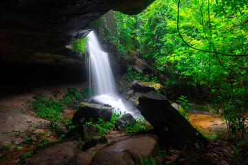 Obraz premium A small waterfall in the deep forest of the border of Thailand and Cambodia,ASIA.Khun Sri waterfall in tropical forest,Sisaket province,Thailand. Leaf moving low speed shutter blur.
