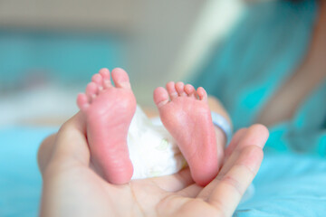 Parent holding in the hands feet of newborn baby, The love and generosity of a mother for her child.