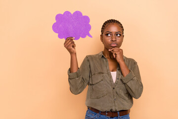 Photo of minded creative girl hand touch chin hold paper cloud card look empty space isolated on beige color background