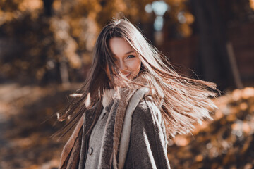 Profile photo of cute brown hairdo millennial lady walk in park wear coat scarf at the street in...