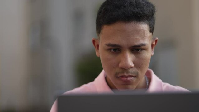 Closeup Face Of A Brazilian Young Man Staring At Laptop Screen Working Remotely. South American Hispanic Male Person Concentrated Studying