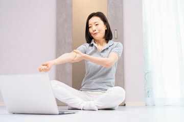 パソコンを見ながら軽い運動をする女性