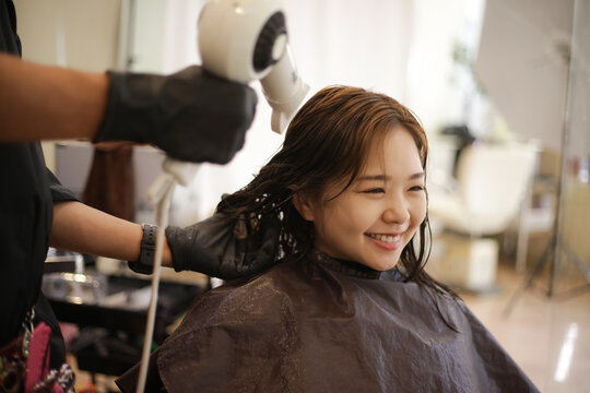 女性の髪にドライヤーをかける男性美容師