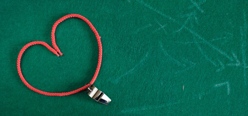 Love for soccer concept.Whistle of soccer referee or coach on green background and heart...