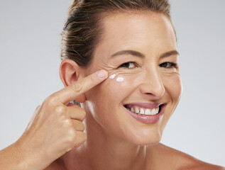 Mature model, skincare and cream on face for beauty, health and happiness with studio background....