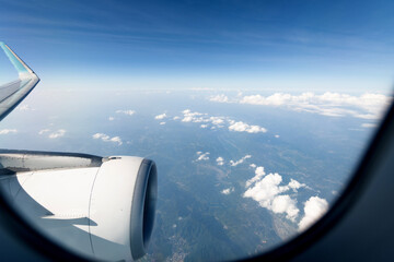 Naklejka na ściany i meble Clouds and mountains view through airplane window
