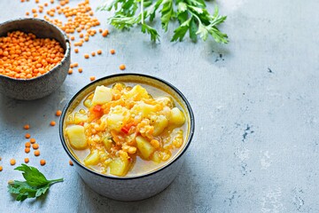 Soup with red lentils and vegetables in a bowl on a blue background.Traditional dish of Turkish or Arabic cuisine, vegan healthy food.