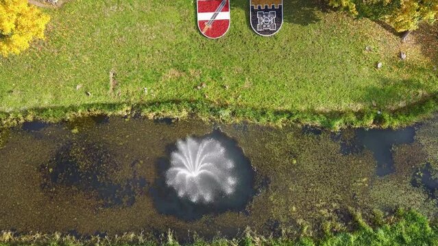 Aerial View of the Dobele City, Ancient Medieval Castle Park With Fontain Latvia. Aerial Panorama of Dobele City Sunny Autumn Day Landscape 4K. Camera Moves Down