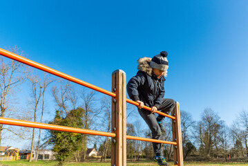 jeune garçon grimpant sur une structure en bois, sport en extérieur