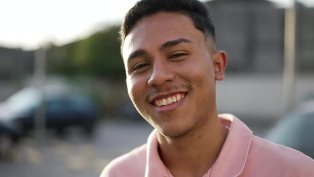 Portrait of a happy hispanic young man smiling at camera standing outdoor. One casual South American male person. Brazilian guy